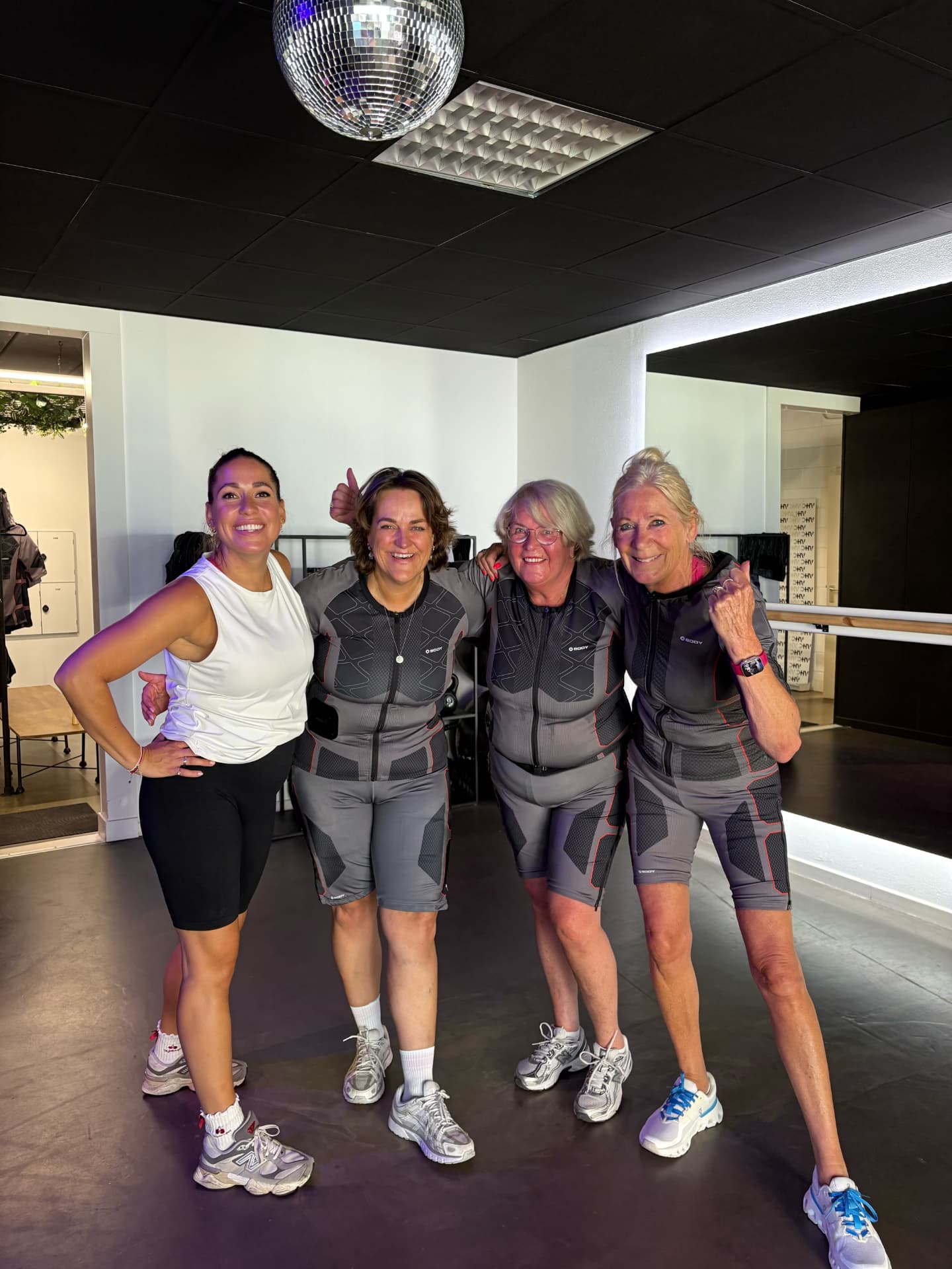 Groep vrouwen in EMS-pakken poseert samen in de studio